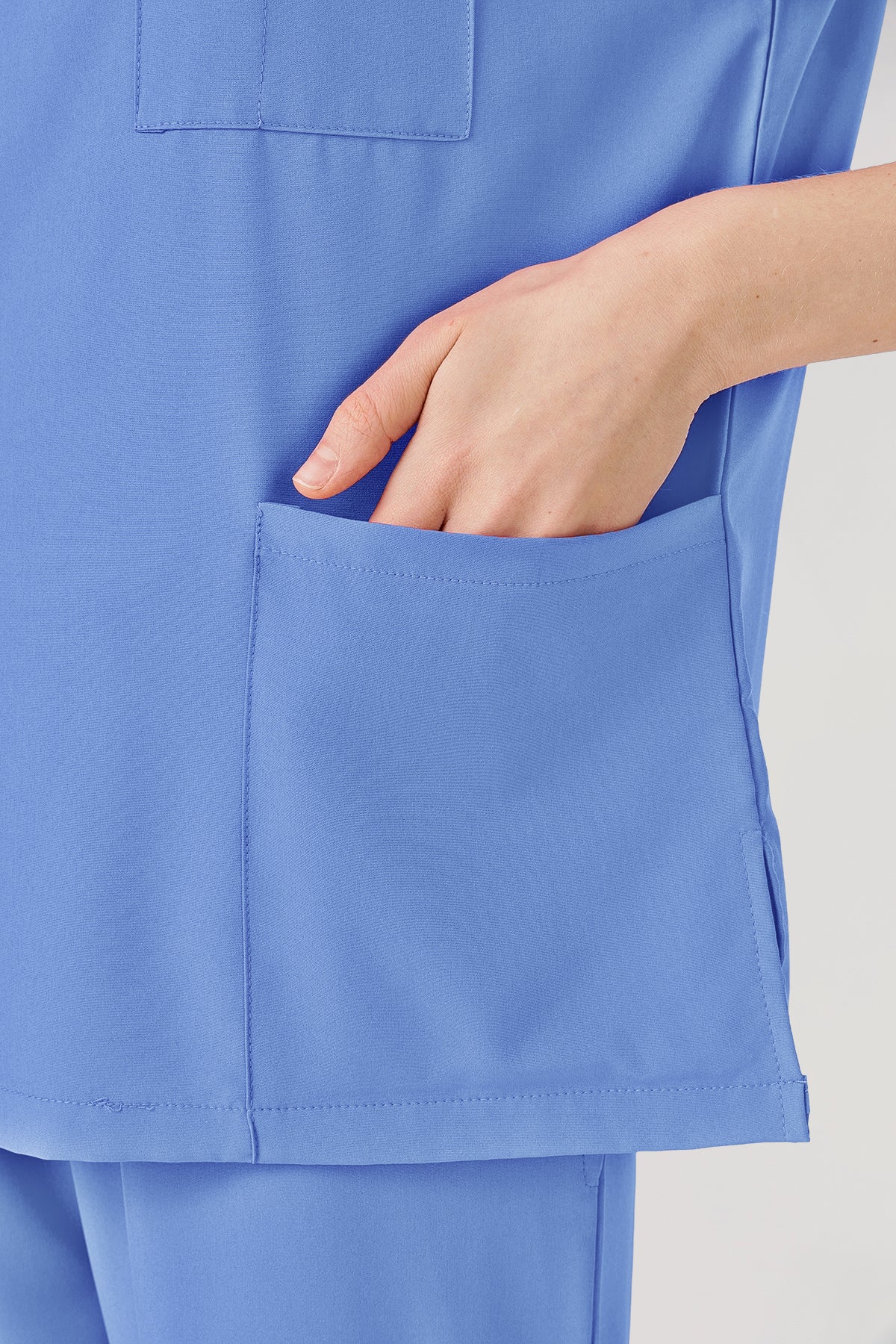 Bata quirúrgica de mujer de color azul claro, detalles de bolsillos mostrados