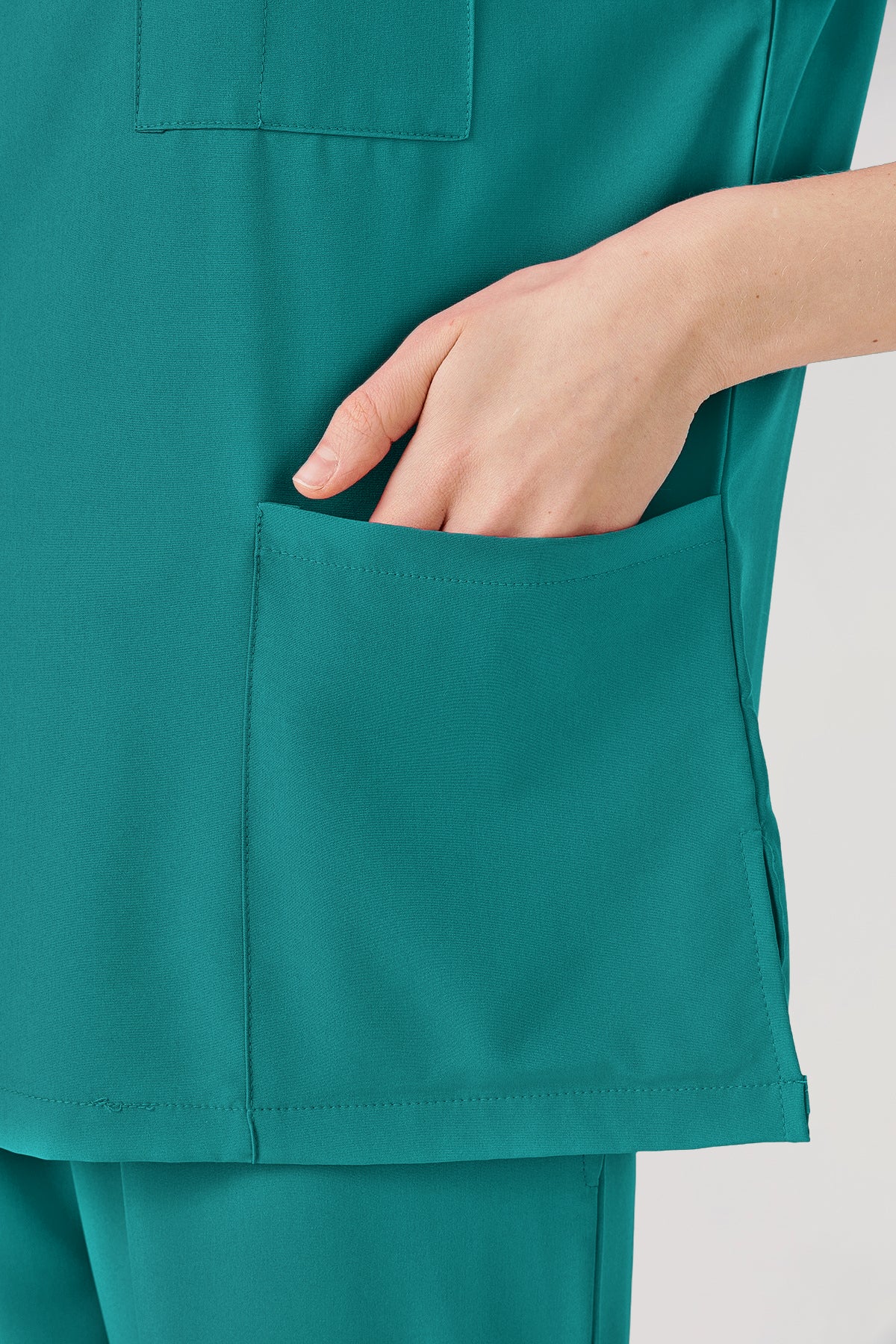 Uniforme médico de mujer verde esmeralda con bolsillos grandes.