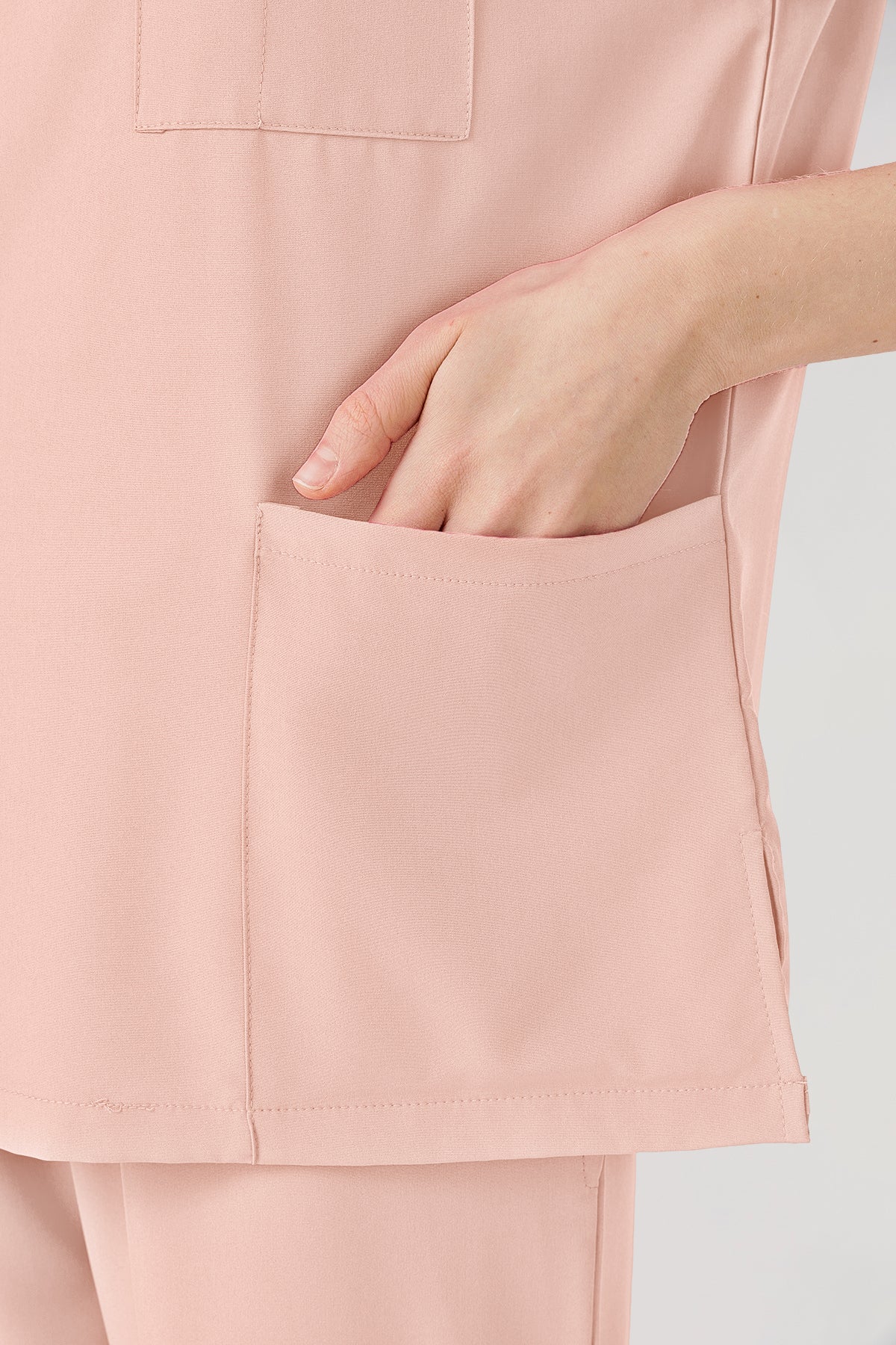 Uniforme médico rosa de mujer con bolsillos superiores visibles